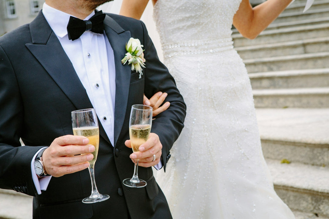 A groom holding two glasses of Champagne