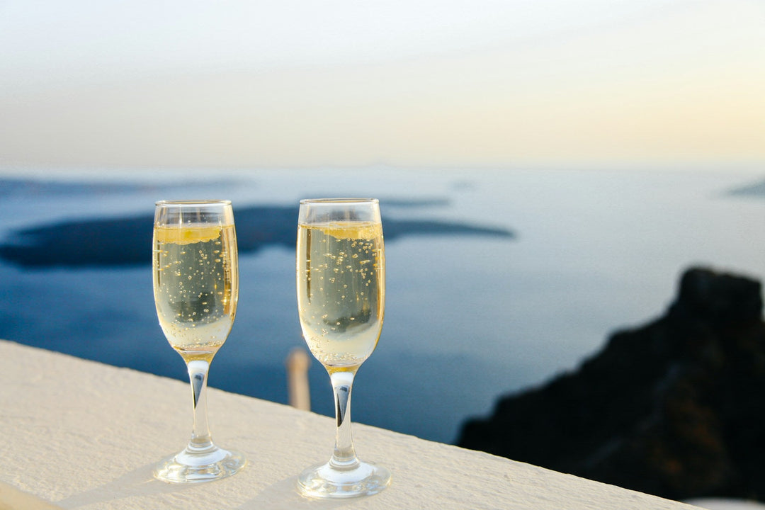 two glasses of sparkling sitting on a table overlooking the ocean