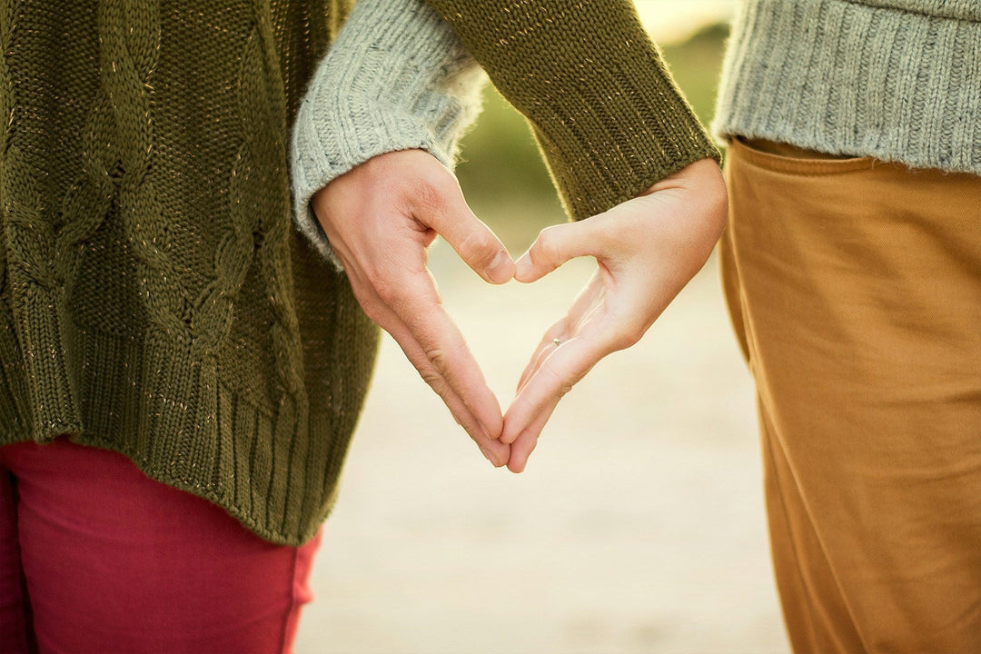 two people in love touching hands to make a heart shape